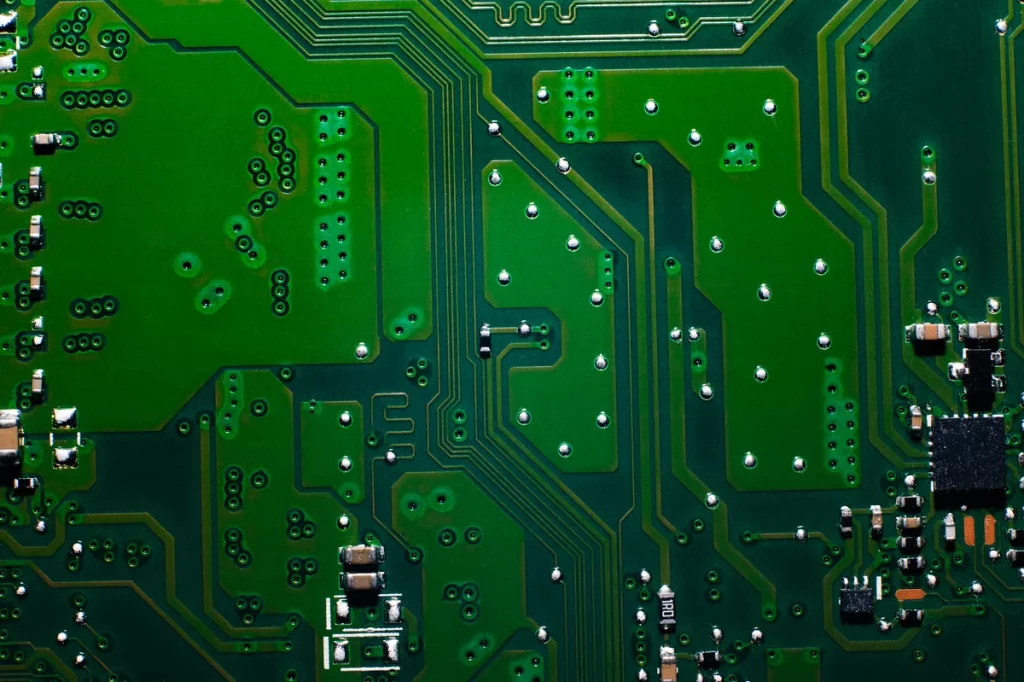 Close-up of a green printed circuit board with visible traces, solder points, and various electronic components.