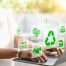 Person typing on a laptop with green eco-friendly and recycling icons digitally overlaid, symbolizing sustainability and environmental awareness.