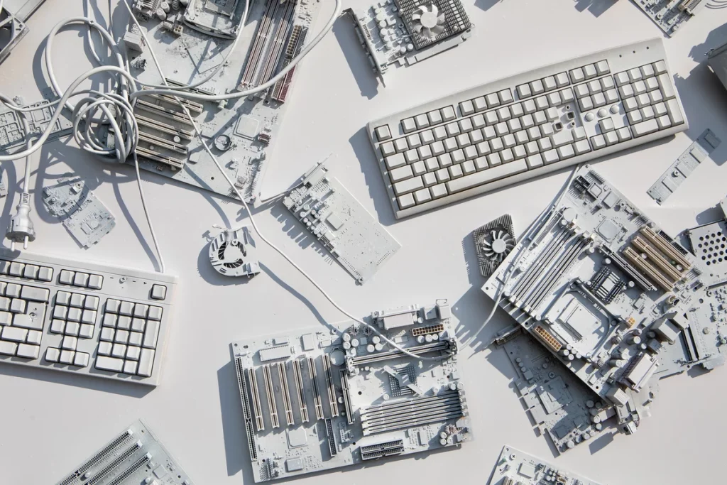 Disassembled computer keyboards and circuit boards are laid out on a white surface, with cables coiled among the components.