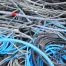 A tangled pile of various colored electrical cables and wires, including blue, gray, black, and red, mixed together chaotically.