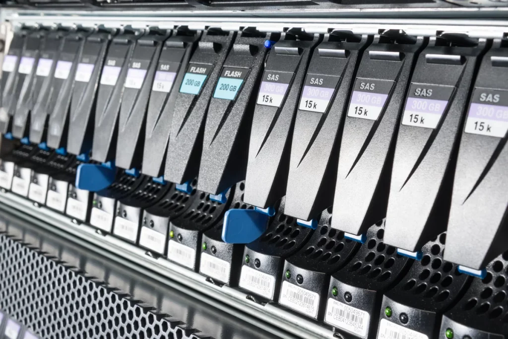 Close-up view of multiple hard drives installed in a server rack, each labeled with storage capacity and type, illuminated by bright light.