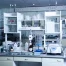 A clean, modern laboratory with glassware, scientific equipment, and chemicals neatly arranged on counters and shelves.